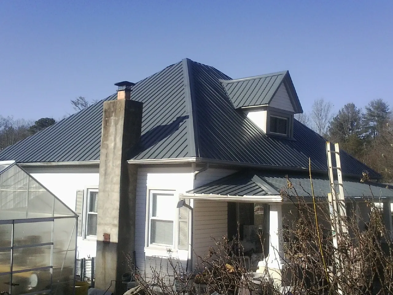 Dark blue standing seam metal roof on a white farmhouse with dormer — Slate & Tile Roof Repair by Roofing Brothers in Lykens