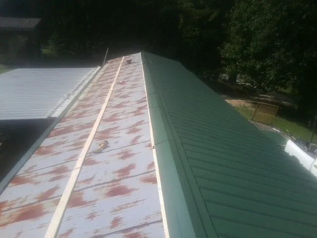 Old rusted panels beside newly installed green metal roofing — Wind Damage Roof Repair by Roofing Brothers in Lykens