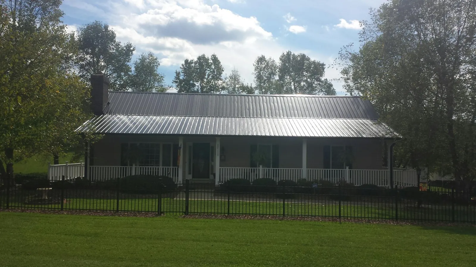 Gray metal roof on a brick ranch with a full width front porch — Gutter Guard Installation work by our crew in Lykens