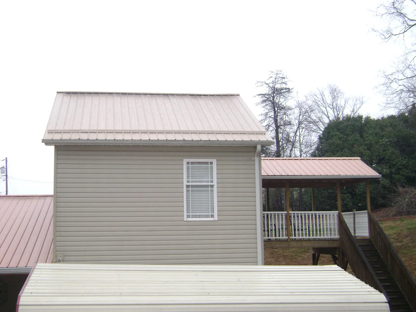 Tan metal roofs on a two story addition and attached porch, from a Roof Replacement job in Lykens