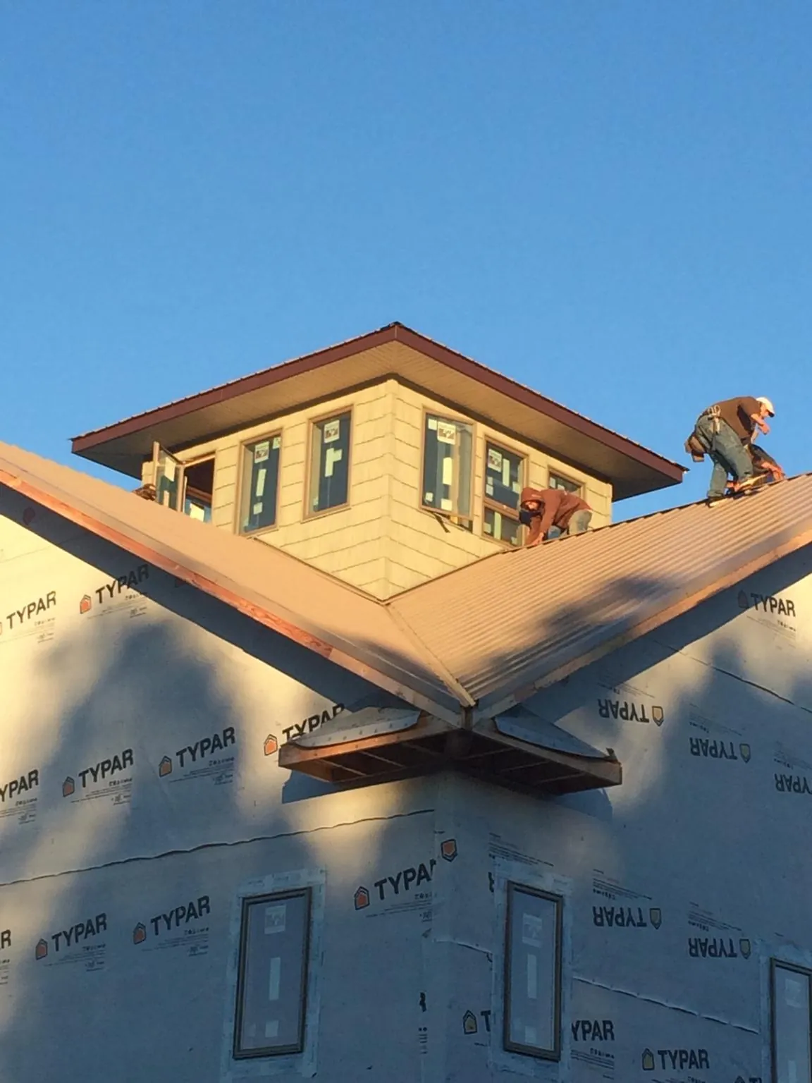 Roofers working around a rooftop cupola on a new metal roof at sunset — Roof Waterproofing in Lykens by Roofing Brothers